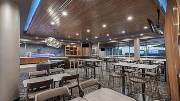 A spacious dining area with multiple tables and chairs, a reception desk, and a large window providing a view of the outdoors.