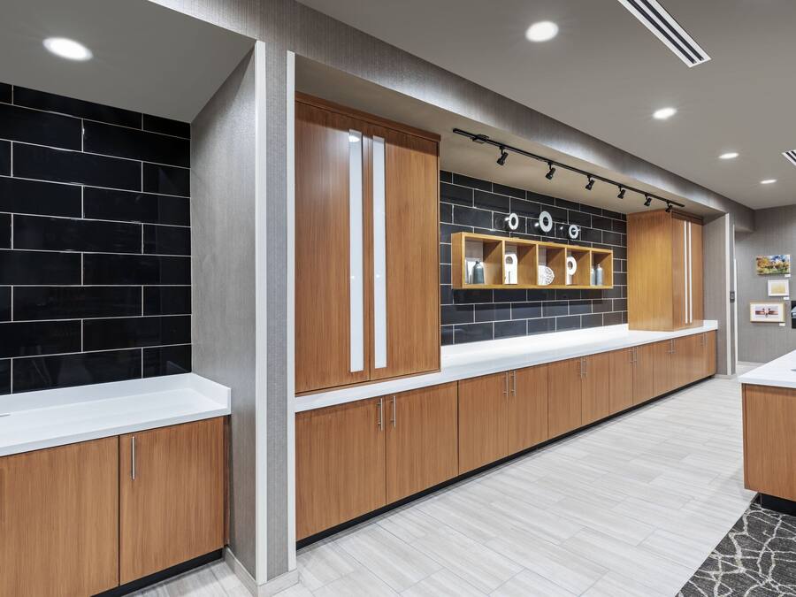 A modern kitchen with wooden cabinets, black tiled backsplash, and a white countertop.