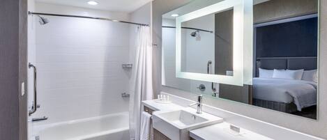 A modern bathroom with a bathtub, two sinks, and a large mirror.