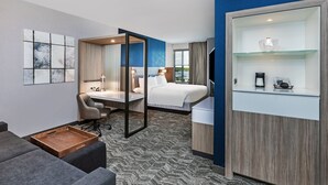 Habitación de hotel con cama, escritorio, silla y una mesita de madera.