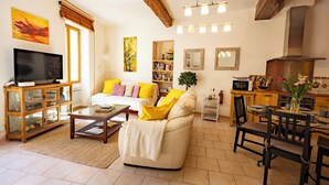 A living room with a sofa, television, and a dining area with chairs and a table. - La Baume des Pèlerins (Sablet)