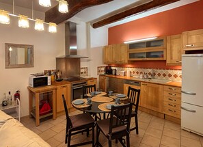 Une cuisine avec des meubles en bois, un four à micro-ondes, une cuisinière et une table à manger avec des chaises.