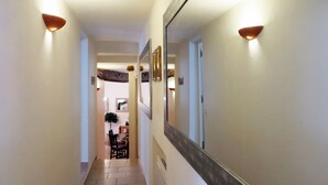 A narrow hallway with a dining area at the end, featuring a table and chairs. - La Baume des Pèlerins (Sablet)
