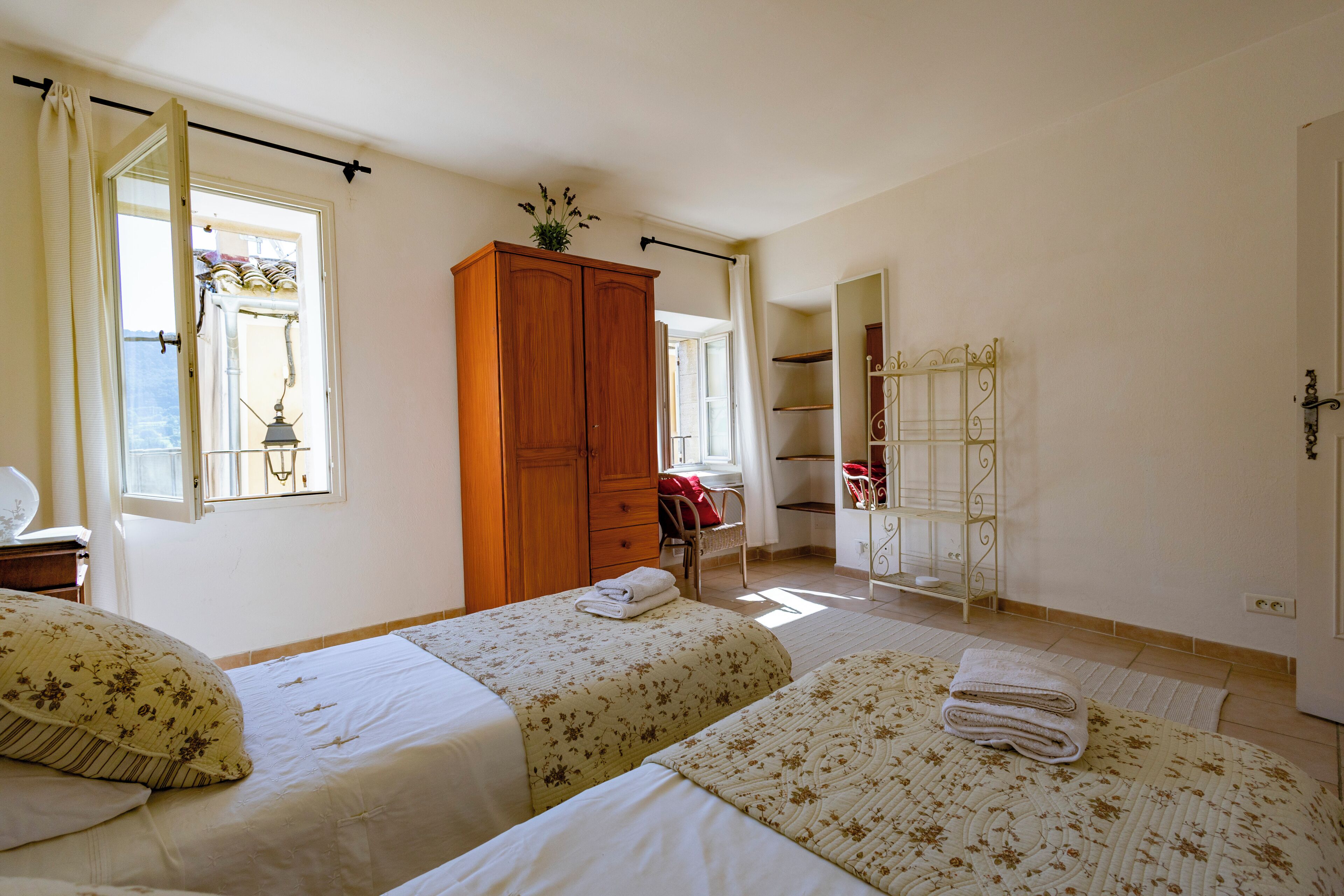 Une chambre avec deux lits, une armoire, une chaise et un miroir.