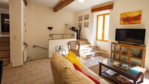 A living room with a sofa, a coffee table, a television, and a staircase. - La Baume des Pèlerins (Sablet)
