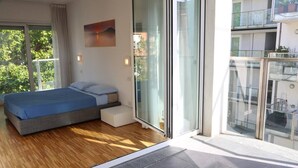 A modern bedroom with a bed, a small seating area, and a large sliding glass door leading to a balcony. - Vela Suites H Milan center with garage (Milano)