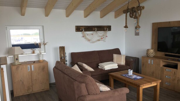 Ett mysigt vardagsrum med en brun soffa, ett träbord och en tv som står på ett träskåp.