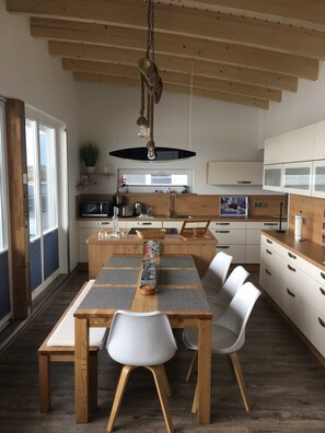 Une cuisine moderne dotée d’un îlot central, de meubles blancs et d’un luminaire suspendu.