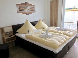 Une chambre d’hôtel avec un grand lit, deux oreillers, une table de chevet avec une lampe et un tableau au mur.