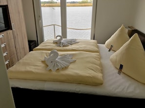 Une chambre d’hôtel avec deux lits, chacun agrémenté d’une serviette en forme de cygne et d’un oreiller.