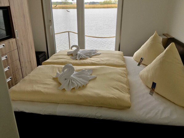 A hotel room with two beds, each with a swan-shaped towel and a pillow.