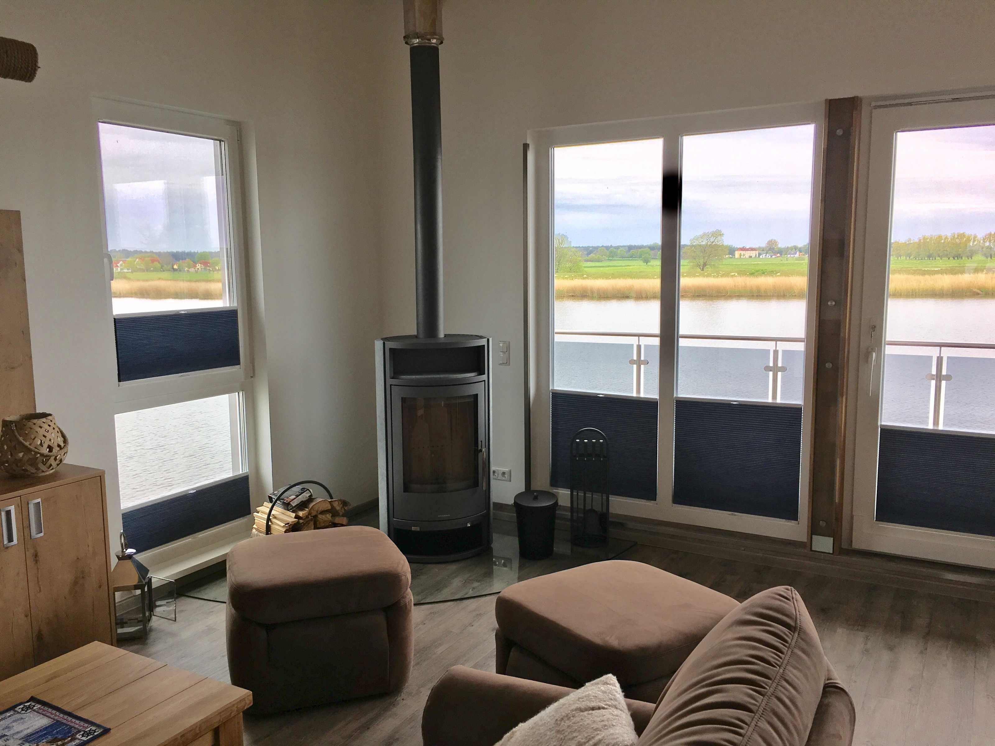 A living room with a fireplace, large windows, and a view of a lake.