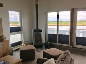 Un salon doté d’une cheminée, de grandes fenêtres et offrant une vue sur un lac.