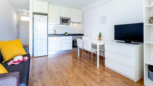 Un espace de vie compact comprenant un coin cuisine, un coin repas et un coin salon avec un téléviseur.
