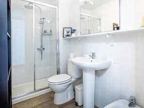 A modern bathroom with a glass shower enclosure, a white toilet, a pedestal sink, and a mirror above the sink. - 32. Bright Copacabana ocean view, free WiFi (Adeje)