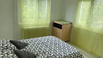 A bedroom with a bed, a dresser, and a window with yellow curtains.
