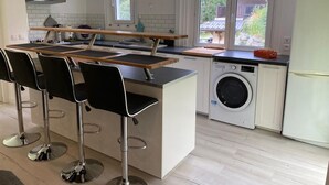 Eine moderne Küche mit einer zentralen Kochinsel, Barhocker, einer Waschmaschine und einem Kühlschrank.