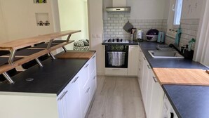Eine moderne Küche mit weißen Schränken, einer schwarzen Arbeitsplatte, einem Einbauofen und einer Waschmaschine.
