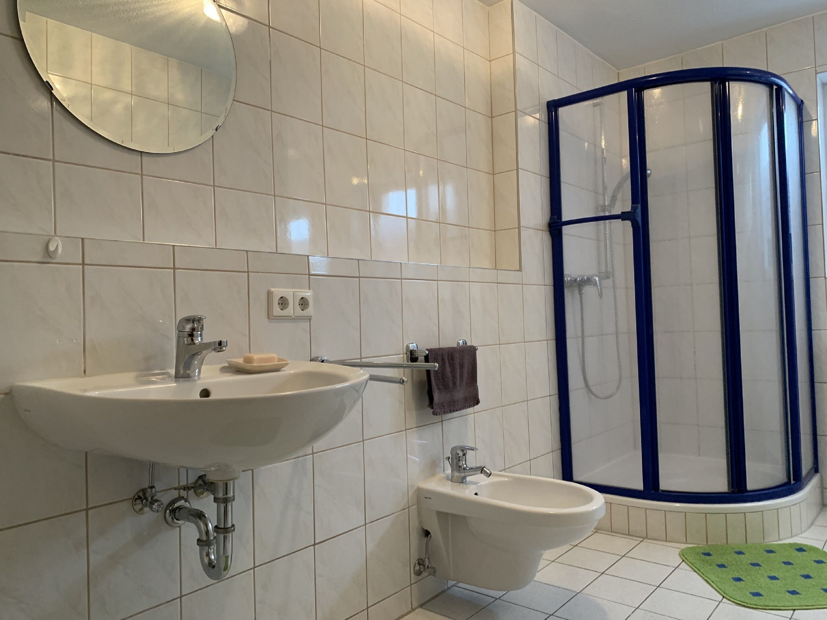 A bathroom with a sink, bidet, and a shower enclosure.