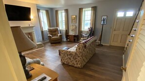 Un salon spacieux avec une cheminée, un canapé, un fauteuil et une table.