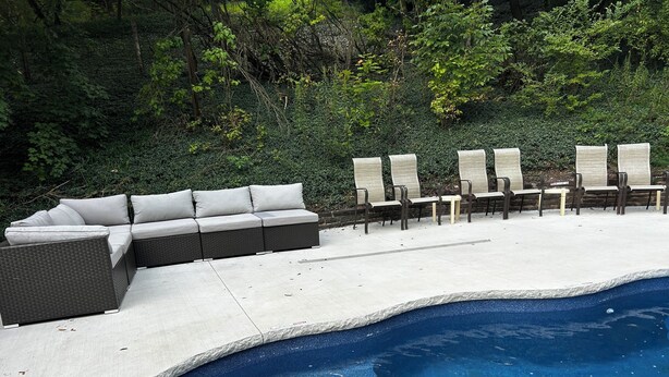 Un espace aménagé au bord de la piscine, avec un canapé intégré et plusieurs chaises longues.