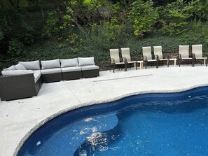 Uma área de piscina com espreguiçadeiras e um sofá embutido.