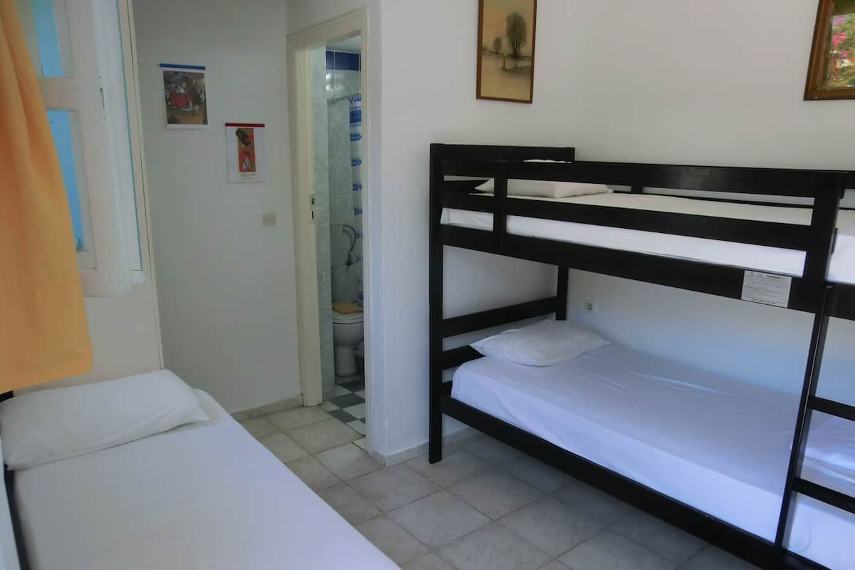A bunk bed room with a bathroom visible through an open door.