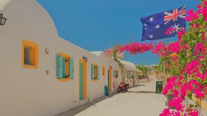 A narrow street with white buildings, turquoise shutters, and a red scooter parked in front. - Santorini Camping & Hostel (Santorini)