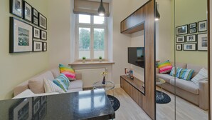 Een moderne woonkamer met een bank, een salontafel, een televisie en ingelijste foto's aan de muur.