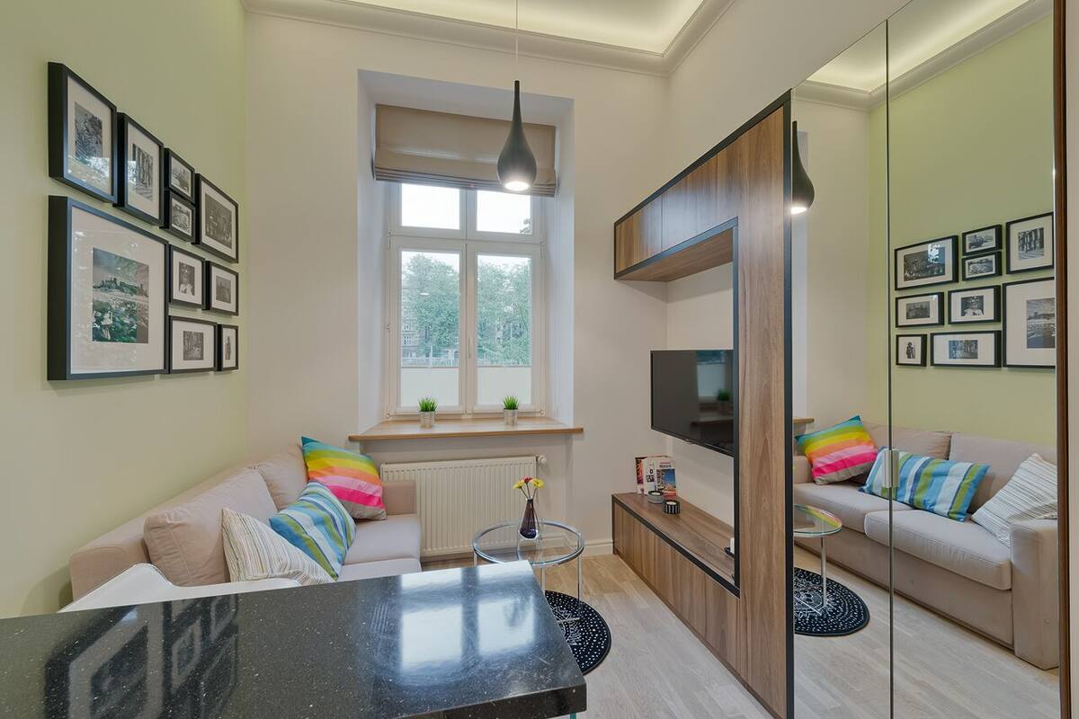 Una sala de estar moderna con un sofá, una mesa de centro, un televisor y cuadros en la pared.