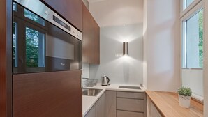 Een moderne keuken met een ingebouwde oven, roestvrijstalen apparatuur, een houten aanrechtblad en een raam voor natuurlijk licht.