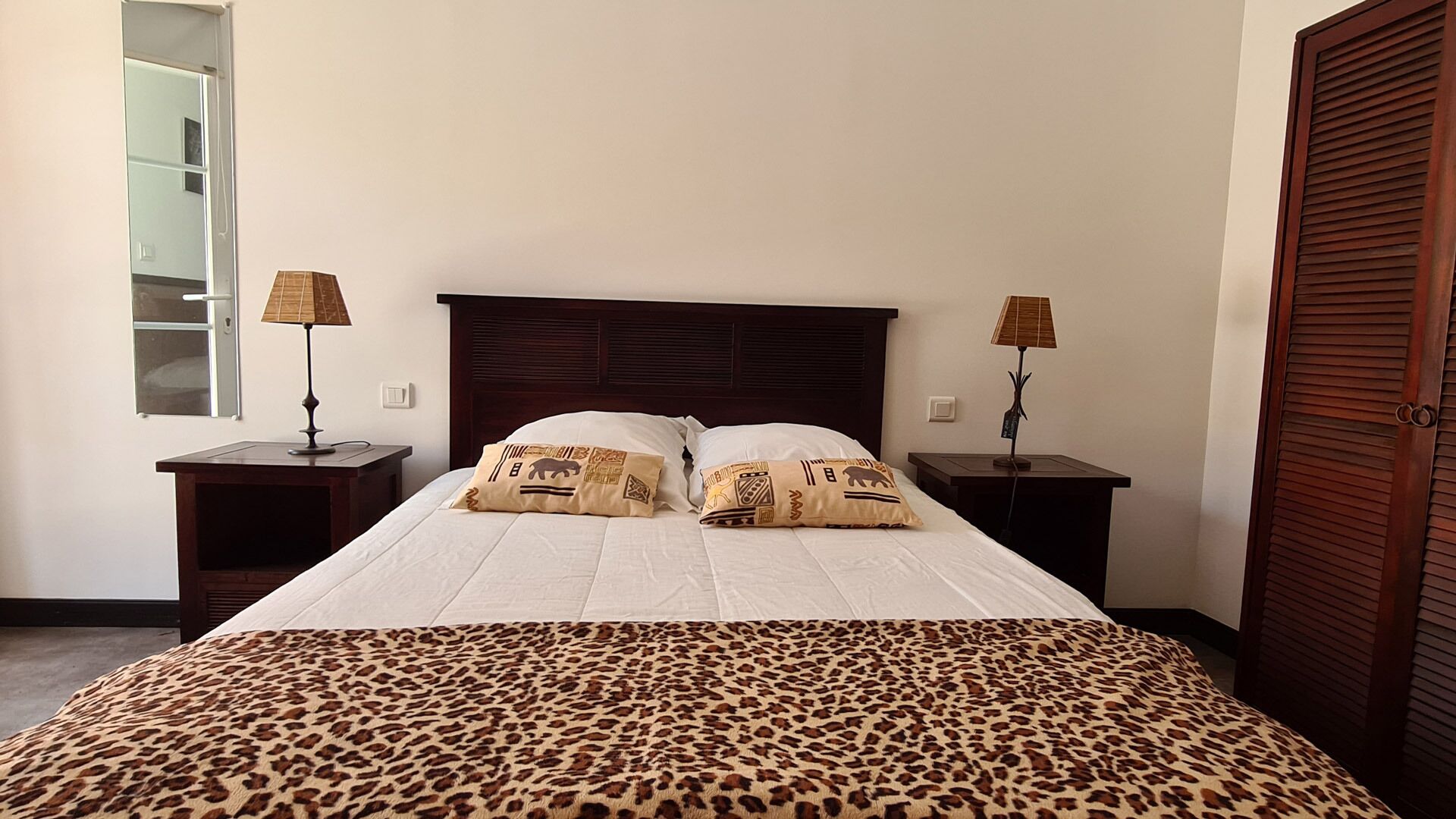 Une chambre à coucher avec un grand lit, deux tables de chevet, une tête de lit en bois et une fenêtre.
