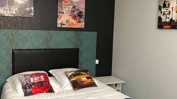 A modern hotel room with a large bed, two pillows, a nightstand, and wall art depicting Las Vegas and a hotel.