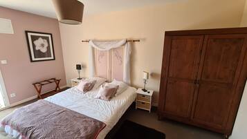 A bedroom with a four-poster bed, bedside tables with lamps, a large wardrobe, and a framed picture on the wall.