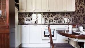 A kitchen with white cabinets, a wooden chair, and a dining table.