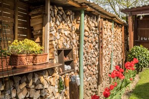 Un edificio rústico con pared de piedra, estantes de madera y una planta en maceta.