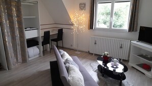 Een moderne woonkamer met een bank, fauteuils, een salontafel en een televisie.