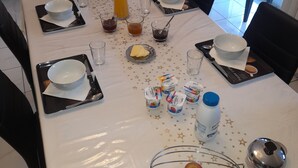 Een ontbijttafel gedekt met diverse producten, zoals fruit, toevoegingen en drankjes.