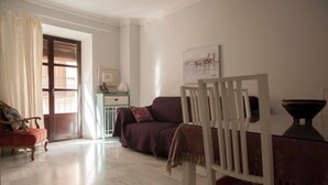 A living room with a wooden chair, a sofa, a small table, and a cabinet. - Center, luminous apt - 2 bathrooms (Sevilla)