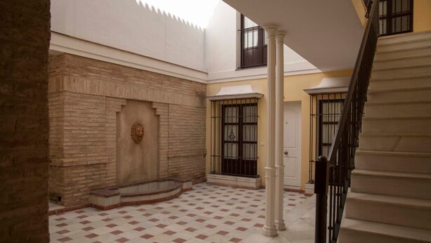 A spacious courtyard with a checkered floor, a central fountain, and a staircase leading to an upper level. - Center, luminous apt - 2 bathrooms (Sevilla)