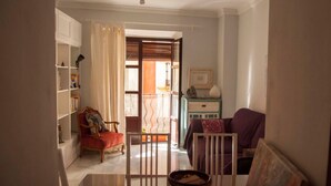 A living room with a red armchair, a purple sofa, a white cabinet, and a glass door leading to a balcony. - Center, luminous apt - 2 bathrooms (Sevilla)