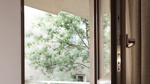 Blick von einem Balkon mit Fliesenboden, einer weißen Laterne und einem Baum im Freien.