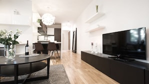 Ein modernes Wohnzimmer mit einem dunklen Holzes Esstisch, einer schwarzen Unterhaltungseinheit und einem großen Flachbildfernseher.
