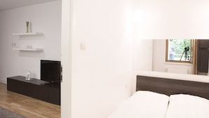 Ein modernes Schlafzimmer mit Bett, Fernseher und Fenster mit Stativ.