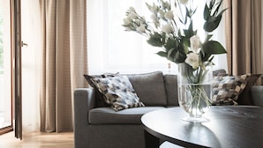 Ein modernes Wohnzimmer mit einem grauen Sofa, einem runden Tisch und einer Vase mit weißen Blumen.