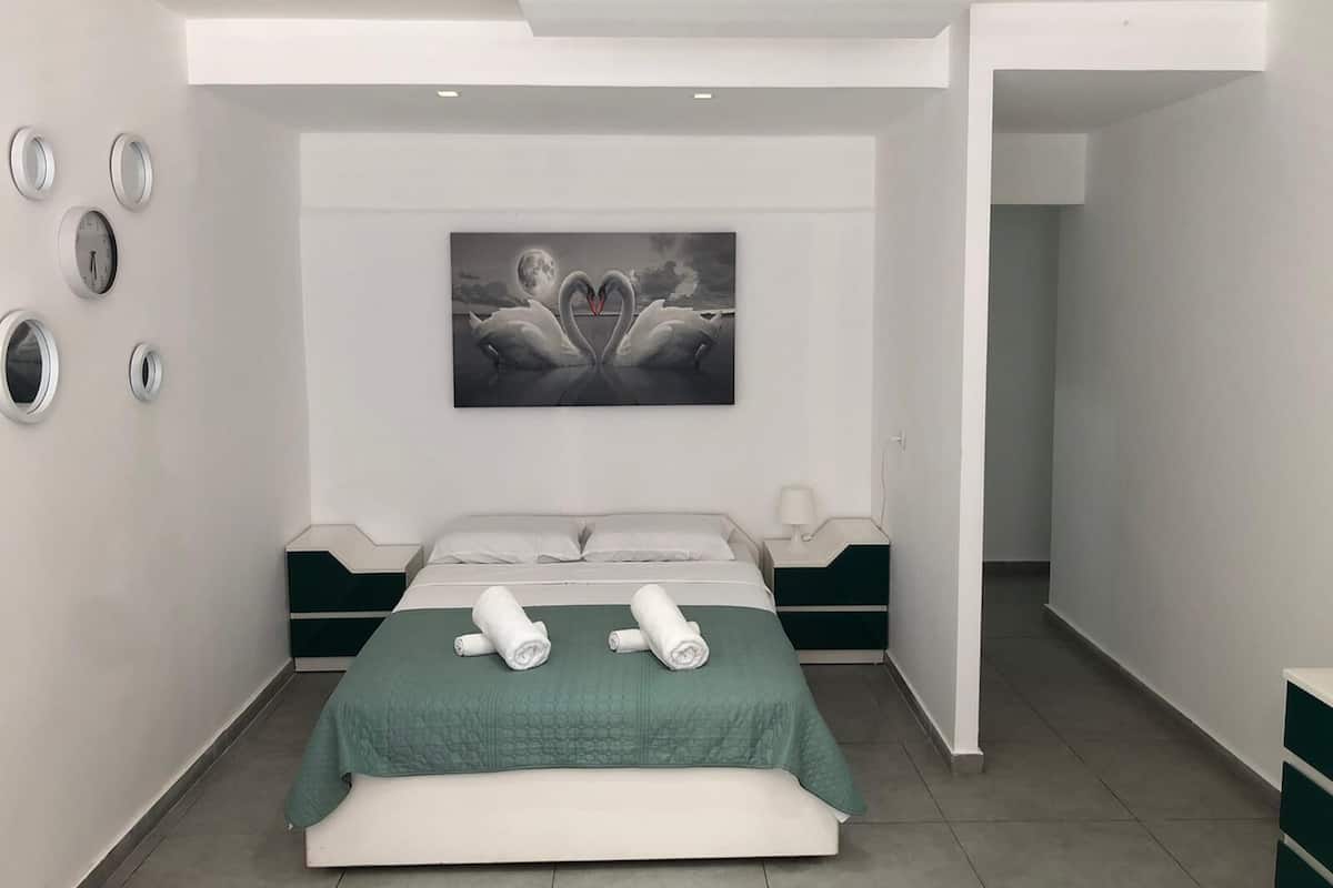 Ein modernes Schlafzimmer mit einem großen Bett, einem Schwane-Gemälde und einer grünen Akzentwand.