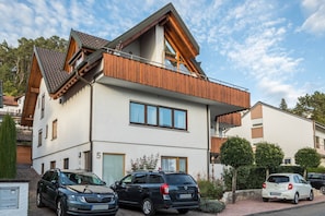 A modern two-story house with a balcony, a garage, and a driveway.