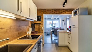 Een moderne keuken met witte kasten, een houten aanrecht en een bakstenen muur.