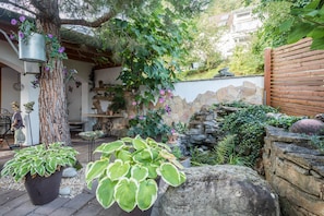 A garden with potted plants, a stone wall, and a wooden fence.