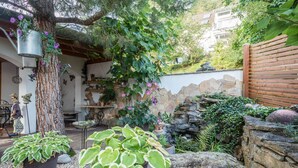 A garden with potted plants, a stone wall, and a wooden fence.